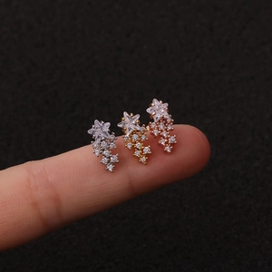 Vista macro di tre orecchini a stella con zirconi in finitura argento, oro e oro rosa
