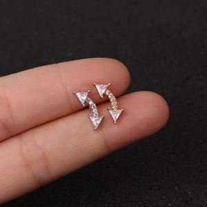 Macro shot of curved stainless steel ear studs with sparkling zircon stones in gold and silver