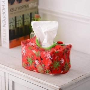 Festive red Christmas tissue box cover with snowflake patterns on a vintage cabinet