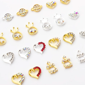 Detailed flat lay of alloy nail art charms with heart, crown, and planet designs