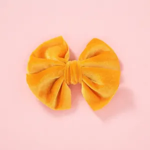 Soft velvet bow hair clip for girls in bright yellow on a pastel pink background