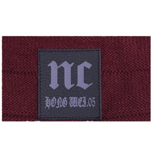Close-up of wine red knit beanie fabric texture with black leather logo label detail