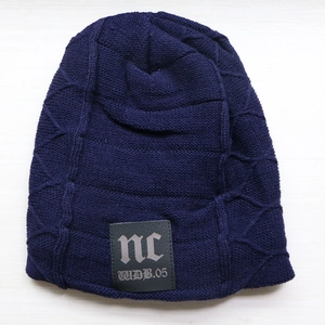 Close-up of navy blue knit beanie featuring a black leather logo patch with NC text