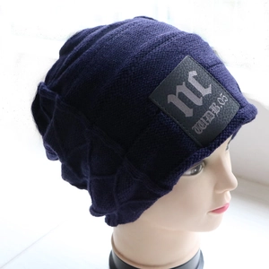 Detail of navy knit beanie with premium faux leather logo patch and ribbed texture