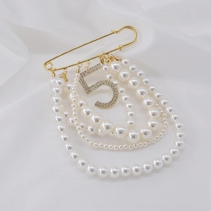 Elegant pearl tassel brooch with sparkling crystal number five on white silk background