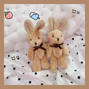 Close-up of soft plush rabbit pendants in light brown with silk bows on knit fabric