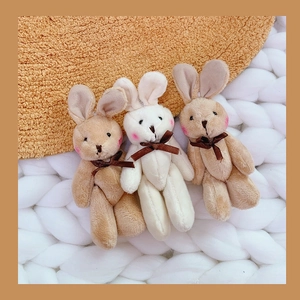 Detailed close-up of cute plush bunny keychains with satin bows in soft beige and cream