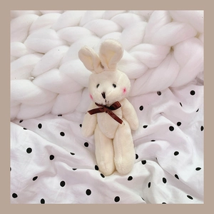 Close-up of a soft white plush bunny pendant with a dark brown silk bow and pink ear details