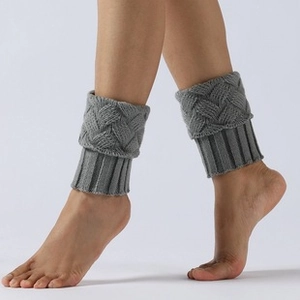 Close-up of gray knitted leg warmers showing thick wool texture and cable knit details
