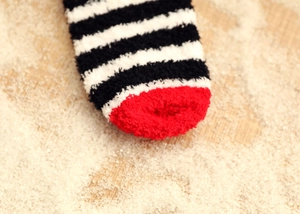 Macro view of plush coral fleece sock fibers in black and white stripes with a red toe