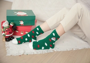 Close-up of green coral fleece Christmas socks with Santa embroidery on white rug