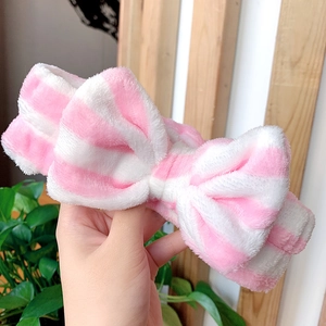 Detailed view of pink and white striped plush headband featuring a large bow knot accessory