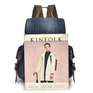 Zaino retrò in denim blu scuro con cinturini marroni, mostrato con rivista su sfondo bianco