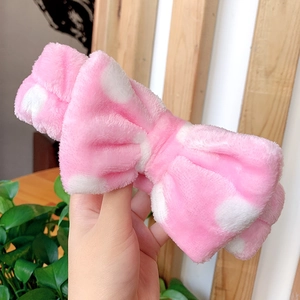 Close-up of pink polka dot plush headband with a large bow for skincare and makeup