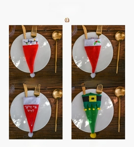 Detail of four Christmas hat cutlery holders with festive embroidery on a wooden table