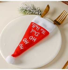 Close-up of a festive red Christmas hat cutlery holder with Ho Ho Ho embroidery on a plate