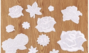 Detailed view of white rose and floral embroidery patches set on wood background