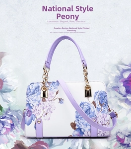 Detail of shell handbag featuring purple floral print and gold chain strap connector