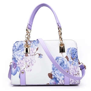 White floral women's handbag with purple handles and detachable strap in a studio shot