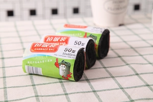 Close-up of three rolls of thickened 50x60cm black garbage bags in green packaging