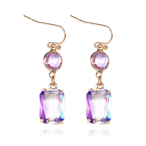 Detailaufnahme geometrischer Ohrringe mit rosa Edelsteinen und blau-violetten Kristallanhängern