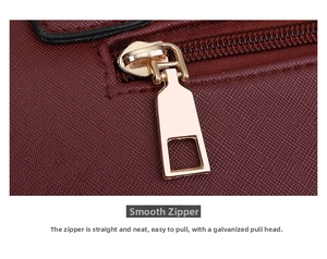 Detailed macro view of the gold plated zipper and stitching on a burgundy handbag