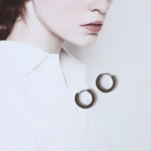 Polished silver stainless steel hoop earrings on a fashion magazine background