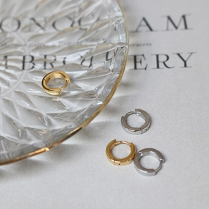 Detail of minimalist 18K gold and silver hoop earrings on a textured glass plate