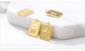 Detail of four gold metal rectangular pendants with embossed star patterns and top rings