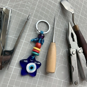 Detail of star-shaped blue glass evil eye keychain with colorful beads on a grey mat
