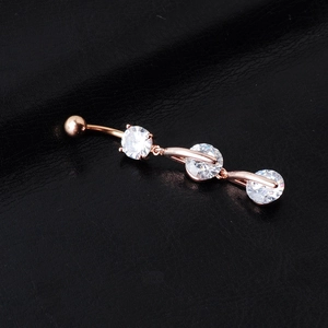 Close-up of rose gold belly ring featuring three sparkling round zircon stones on dark texture