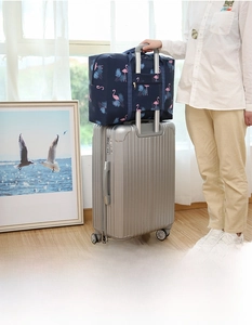 Foldable waterproof travel bag with flamingo print secured on suitcase handle bar