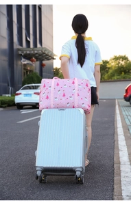 Detail of pink cartoon travel bag attached to luggage handle via trolley sleeve strap