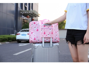 Pink waterproof foldable travel bag with trolley sleeve on luggage and cartoon print