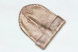 Macro shot of rose gold metallic knit beanie with reflective texture and high shine finish