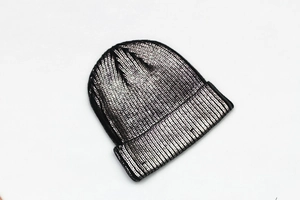 Detailed view of black and silver metallic knit fabric texture on a beanie hat