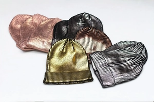 Close-up of metallic knit beanies in gold, silver and bronze with shiny laser finish