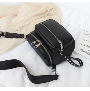 Detailansicht der schwarzen Gürteltasche mit silbernen Reißverschlüssen und breitem Gurt