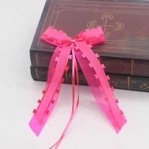 Détail d'un nœud en tulle rose avec accents en forme de cœur et longs rubans sur livres