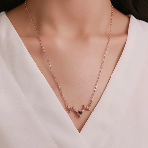 Rose gold antler necklace with projection stone on woman's neck in close-up view