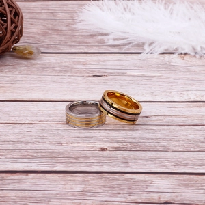Two-tone and tricolor striped stainless steel rings set on light wood background