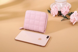 Close-up of pink checkered mini PU leather wallet with zipper detail on warm background