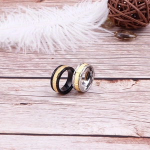 Two-tone black and gold titanium steel ring with brushed metal finish on wood