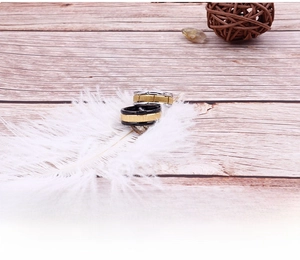 Detail of brushed black and gold titanium rings on a soft white feather background