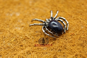 Detailed macro view of silver spider brooch with oval blue sandstone on fiber mat