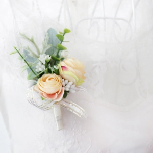 Close-up of champagne silk rose boutonniere with eucalyptus leaves and gold-edged bow