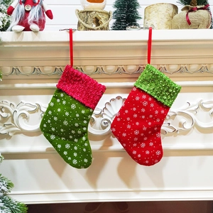 Red and green Christmas stockings with snowflake patterns hanging on a white fireplace mantle