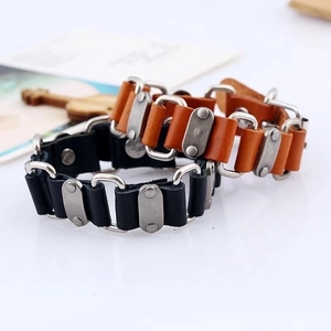 Punk style leather bracelets in black and brown with metal buckles on white surface