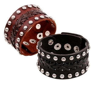 Detalle de brazaletes punk de cuero ancho con tachuelas de metal y textura trenzada