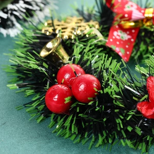 Christmas wreath with green pine needles, red berries, gold bell, and red festive bow